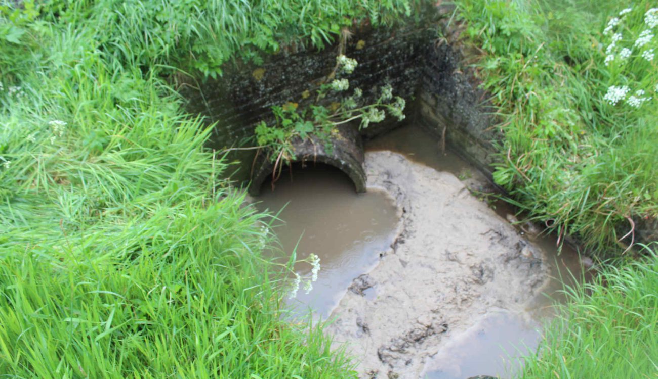 Verstopte duiker met zand en slib