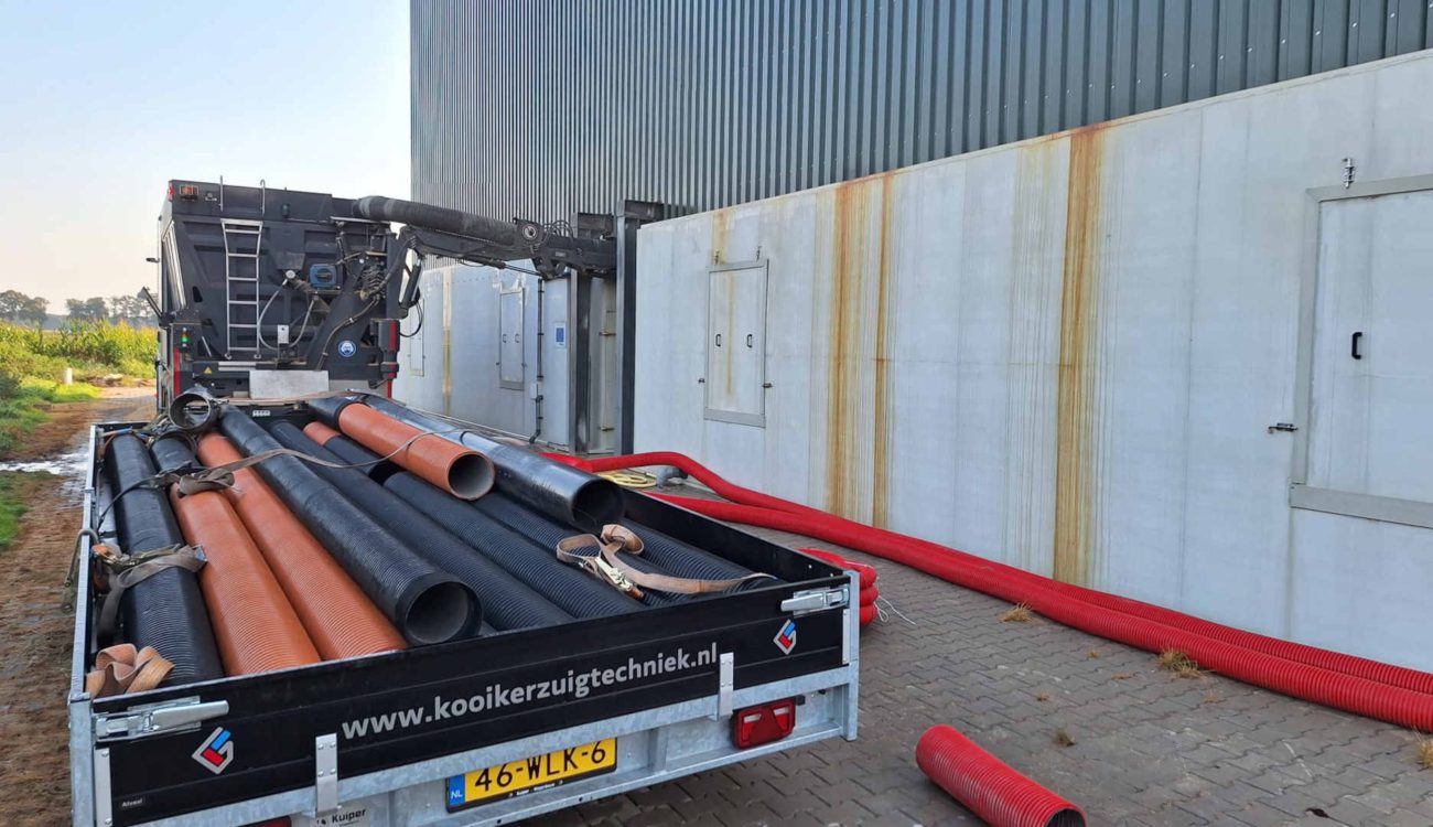 Zuigwagen met materiaal bij varkensschuur in Beerzerveld